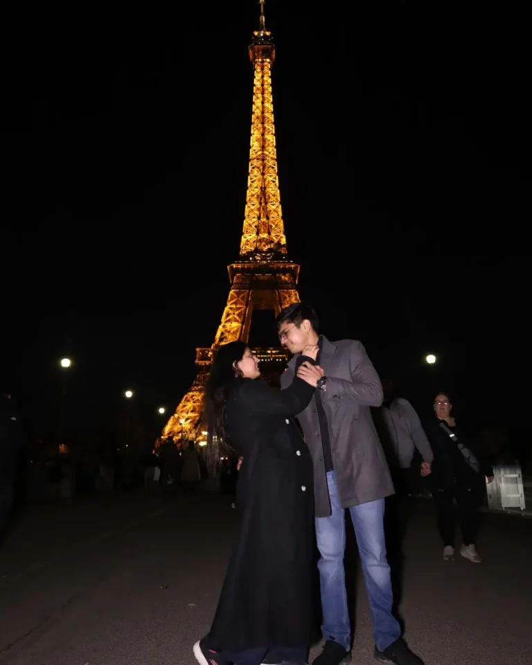 Home 5 Prateek and Dolly, Naviora Journeys clients, in front of the Eiffel Tower lit up at night in Paris