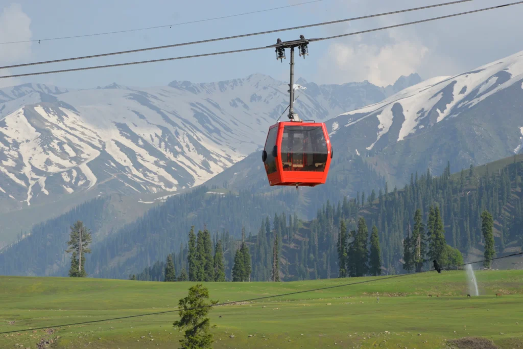 Kashmir Trip Cost from India (2026–27): What a 7-Day Trip Really Costs a Couple 4 A red Gulmarg Gondola cabin above the meadows with snow-capped peaks behind